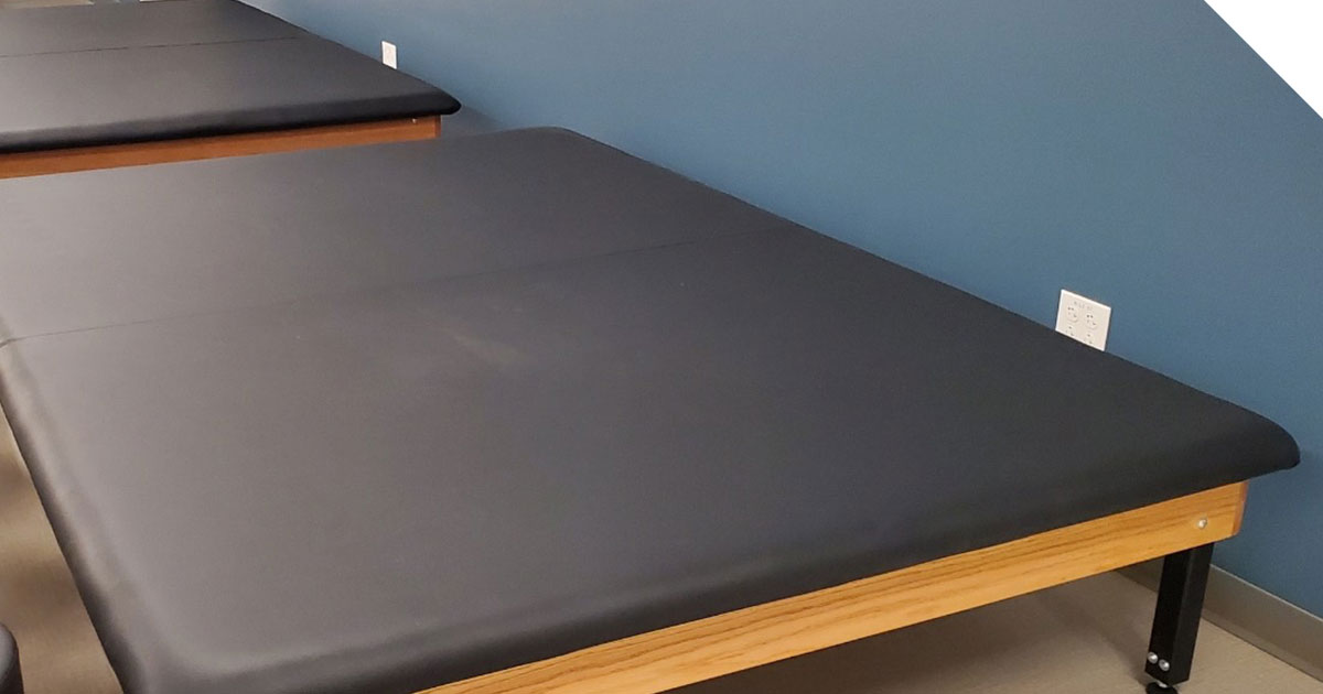 Hi-lo mat table in a physical therapy clinic, used for patient stretching and manual therapy exercises