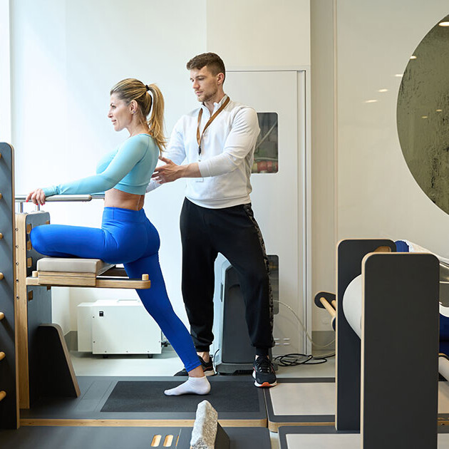 Physical therapist assisting a patient with functional movement training using physical therapy equipment in a modern clinic.